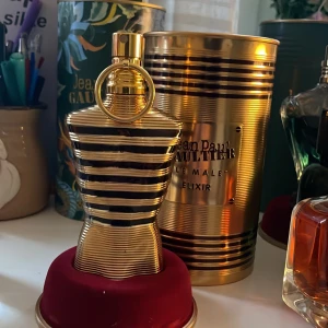 Jean Paul Gaultier Le Male Elixir - Säljer en exklusiv parfym från Jean Paul Gaultier, Le Male Elixir. Flaskan har en unik design i form av en manlig torso med guld- och svartfärgade ränder. Förpackningen är en elegant guldfärgad metallcylinder. Perfekt för den som vill ha en lyxig doftupplevelse. 55-60ml kvar!