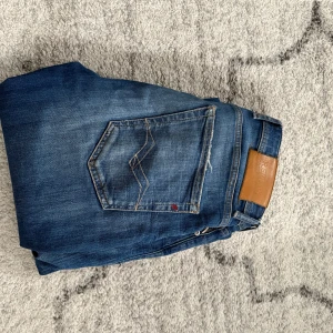 Replay anbass - Snygga blå jeans från Replay med klassisk femficksdesign och en bekväm passform. Jeansen har en lätt tvättad look och en diskret logga på fickan. Perfekta för en avslappnad stil.