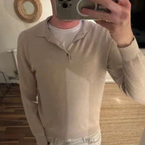 Beige pikétröja från Massimo Dutti - Säljer en stilren beige pikétröja från Massimo Dutti. Tröjan har långa ärmar och en klassisk krage med knappar. Perfekt för en avslappnad men ändå en stilig look. Passar bra till jeans.