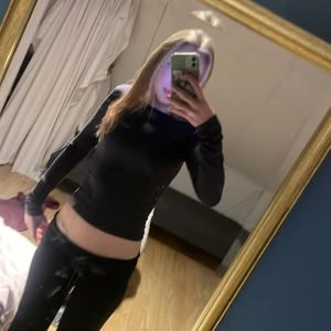 Svart långärmad topp - Säljer en stilren svart långärmad topp. Den har en tight passform och är perfekt för en minimalistisk look. Toppen är gjord i ett mjukt material som känns skönt mot huden.