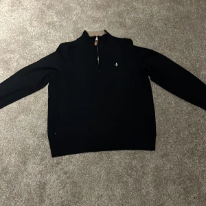 Mörkblå tröja i merinoull från Morris - Säljer en stilren svart tröja från Morris i 100% merinoull. Tröjan har en dragkedja vid halsen och en liten broderad detalj på bröstet. Perfekt för kyligare dagar. Storlek XL men har krympt i tvätten till en XS ungefär. Fortfarande toppskick. Jag är 165cm och väger 50kg. Skriv vid frågor och funderingar. Nypris 1500-2000. Priset går att diskutera! MVH Jacob 