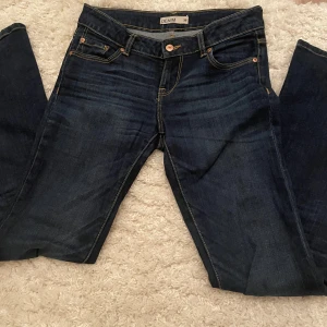 Mörkblå jeans från Lindex - Snygga mörkblå jeans från Lindex med klassisk femficksdesign och kontrastsömmar. De har en knappgylf och är perfekta för en avslappnad stil. Innerbenslängd ca. 81cm🩷 Köpare står för frakten!