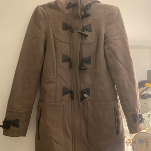 Brun duffel kappa  - Duffeljacka med huva, väldigt skön. Använd ett antal gånger, bra skick. Lite större i storleken. 