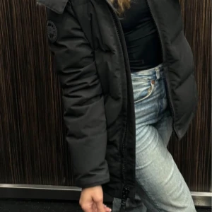 Canada Goose Chelse Parka Black Label - Säljer en svart jacka från Canada Goose med huva och dragkedja. Jackan har en klassisk design med en rund logotyp på ärmen. Perfekt för kalla dagar och håller dig varm och bekväm. 🖤I bra skick och kan mötas upp.