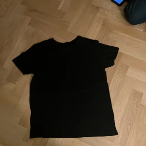 Svart t-shirt - Säljer en klassisk svart t-shirt med korta ärmar. Perfekt basplagg för alla tillfällen. Enkel och stilren design.