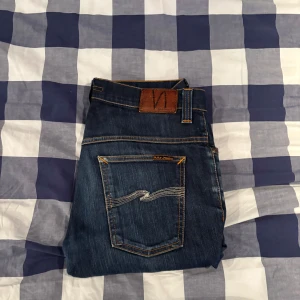 Mörkblå jeans från Nudie Jeans - Mörkblå Nudie jeans i storlek 33/34 sitter mer som 32/31. Modellen är slimfit men mer åt regular hållet. Säljer pga att jag har vuxit ur dem. Nypris 1600kr.