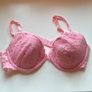 Rosa spets-BH från H&M - Säljer en söt rosa BH från H&M med vacker spetsdetalj. Den har justerbara axelband och en bekväm passform. Perfekt för att lägga till en feminin touch till din garderob.