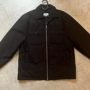 Svart jacka från East west  - Snygg svart jacka från east west med dragkedja och två bröstfickor med knappar. Perfekt för en stilren look. Jackan har långa ärmar och en klassisk krage.