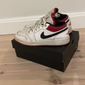 Nike Air Jordans i vitt och rött - Snygga Nike Air Jordans i vitt med röda och svarta detaljer. Skorna har klassisk snörning och den ikoniska Air Jordan-loggan på hälen. Perfekta för dig som älskar en sportig stil med en touch av retro. De är mycket bra skick bara lite smutsiga men lätt att ta bort
