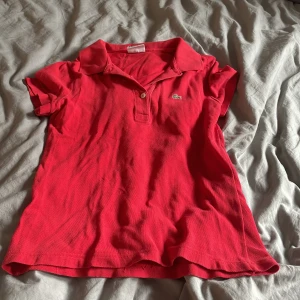 Lacoste T-shirt  - En röd Lacoste T-shirt i st 36(S)