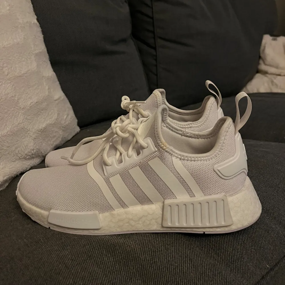 Säljer ett par vita Adidas NMD sneakers i storlek 40. De är i bra skick och har den klassiska NMD-designen med de tre ränderna på sidan. Skorna har en bekväm passform och är perfekta för både vardag och träning. De är tillverkade i syntetmaterial och har en stilren look.. Kengät.