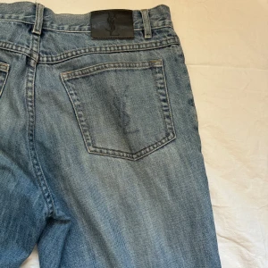 YSL jeans - Rensar min garderob. Säljer mina vintage ysl jeans från 00, storlek 34/30 men är ganska små i midjan dock är ganska baggy. Små slitage främst heelbite.