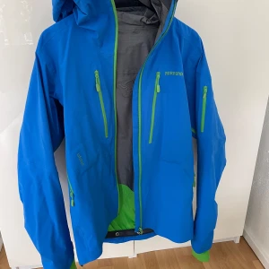 Skaljacka Norrøna  - Grym skaljacka från Norrøna med många smidiga fack och ventilation under armarna. Det finns lite tecken på användning på luvan och armarna men den är generellt i gott skick. Gjord i goretex så den är perfekt till skidbacken eller i regn.