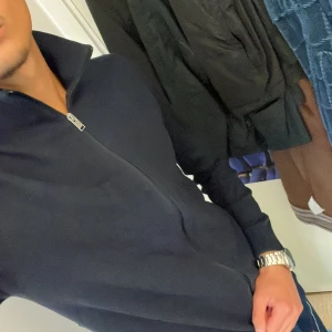 Svart tröja med dragkedja från Selected Homme - Säljer en stilren marinblå tröja från Selected Homme. Den har en dragkedja framtill och är perfekt för både vardag och lite mer uppklädda tillfällen. Tröjan är långärmad och gjord i ett mjukt material som känns skönt mot huden. Passar perfekt till höst, vår och vinter!