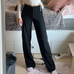 Svarta byxor med hög midja - Säljer ett par snygga svarta kostymbyxor med hög midja. De har en rak passform och är perfekta för både vardag och fest. Byxorna har knapp och dragkedja framtill. Superbekväma och lätta att matcha med olika toppar!