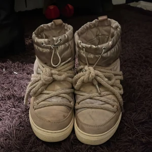 Unika Inuikii vinterboots - Säljer ett par snygga och varma beige vinterboots från Inuikii. De har en quiltad design med snörning och en mysig pälsfodrad insida. Perfekta för kalla vinterdagar! 🥶Kan gå ner i pris🥰