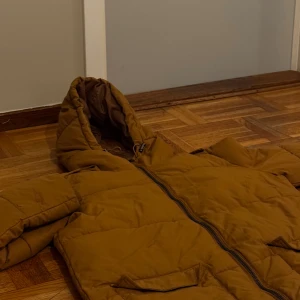 Brun lång pufferjacka Från Object - Säljer en brun lång pufferjacka i mycket bra skick. Den har en dragkedja framtill och två stora fickor. Perfekt för kalla vinterdagar med sin varma vaddering och huva. Endast: 599