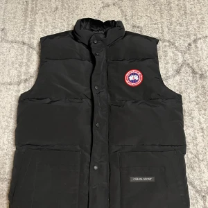 Svart Canada Goose väst - Säljer en helt ny dunväst från Canada Goose i färgen svart. Helt oanvänd, säljes pga att jag köpte fel storlek. Hör av dig vid intresse!