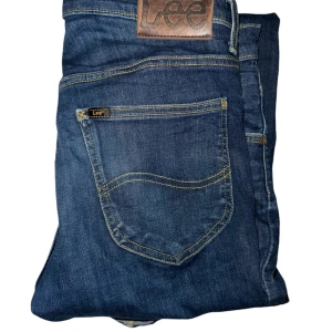 Blå jeans från Lee - Säljer ett par snygga blå jeans från Lee i modellen Daren. De har en klassisk femficksdesign och är tillverkade i slitstarkt denim. Perfekta för både vardag och fest! Hör av er om frågor!!