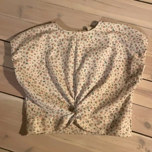 Blommig topp från Zara - Söt blommig topp från Zara i storlek 128. Den har ett knyt framtill och ett litet knapphål bak. Perfekt för vår och sommar med sitt lätta och luftiga material. Blommönstret är i fina pastellfärger och blusen är i mycket bra skick. Jag säljer den för jag har växt ur den. 💞💞 frakt betalar ni själva 😊💞
