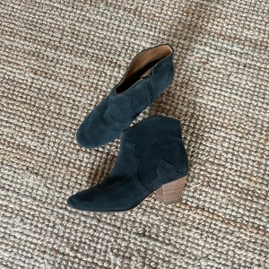 Mörkgröna mocka boots från Isabel Marant Étoile - Säljer ett par snygga mörkgröna mocka boots från Isabel Marant Étoile i storlek 37.5. De har en låg klack och dragkedja på sidan för enkel på- och avtagning. Perfekta för höst och vår, dessa boots är både stiliga och bekväma. Tillverkade i Frankrike med äkta läder.
