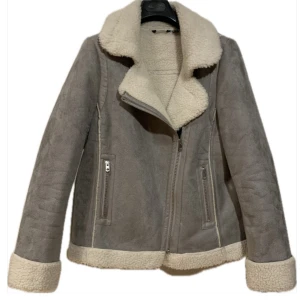 Grå vit Teddy jacka  - väldigt fin, ganska höst jacka som på utsidan har mocka imitation tyg med teddy tyg som dekorationer och på insidan  Väldigt fint skick utan några  defekter minimal tecken på användning  , inga smink elelr andra fleckar Storlek 38-M sitter normal passform 