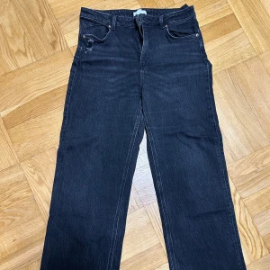 Svarta jeans - Jeans i stretchigt material. Jeansen är midwaist och sitter tajt på låren och lösa längre ner. Sitter ganska kort på mig som är 170cm lång