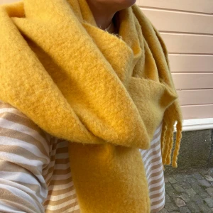 Gul halsduk med fransar - Säljer en supermysig gul halsduk med fransar i ändarna. Perfekt för att liva upp din vinter- eller höstoutfit. Den är mjuk och varm, idealisk för kyliga dagar. Ett måste för garderoben om du älskar färg och komfort!