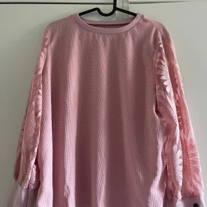 Blommig tröja - En vacker tröja som pryds av blommor i ett fint nätmönster på ärmarna. Storlek XL/42