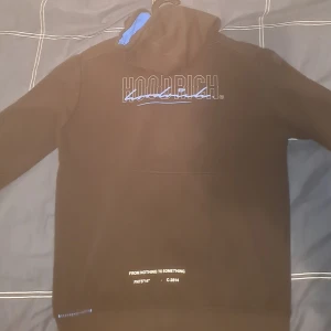 hoodrich  - Hej säljar en hoodrich hoodie med färgen svart o blå då den inte passar längre. Den är storlek S men funkar som XS använt den då och då har en skada på kedjefickan som du kan se på bilden annars inga fler skador. Skriv för mer info eller mer bilder 