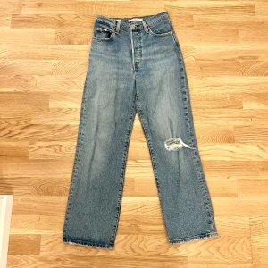Jeans - Snygga Levi's jeans i modellen Ribcage Straight. Jeansen är i en ljusblå färg och har en hög midja. De har en rak passform och har ett medvetet hål vid ena benet. Storlek W 26 / L 27 -  i fint skick. 🤍