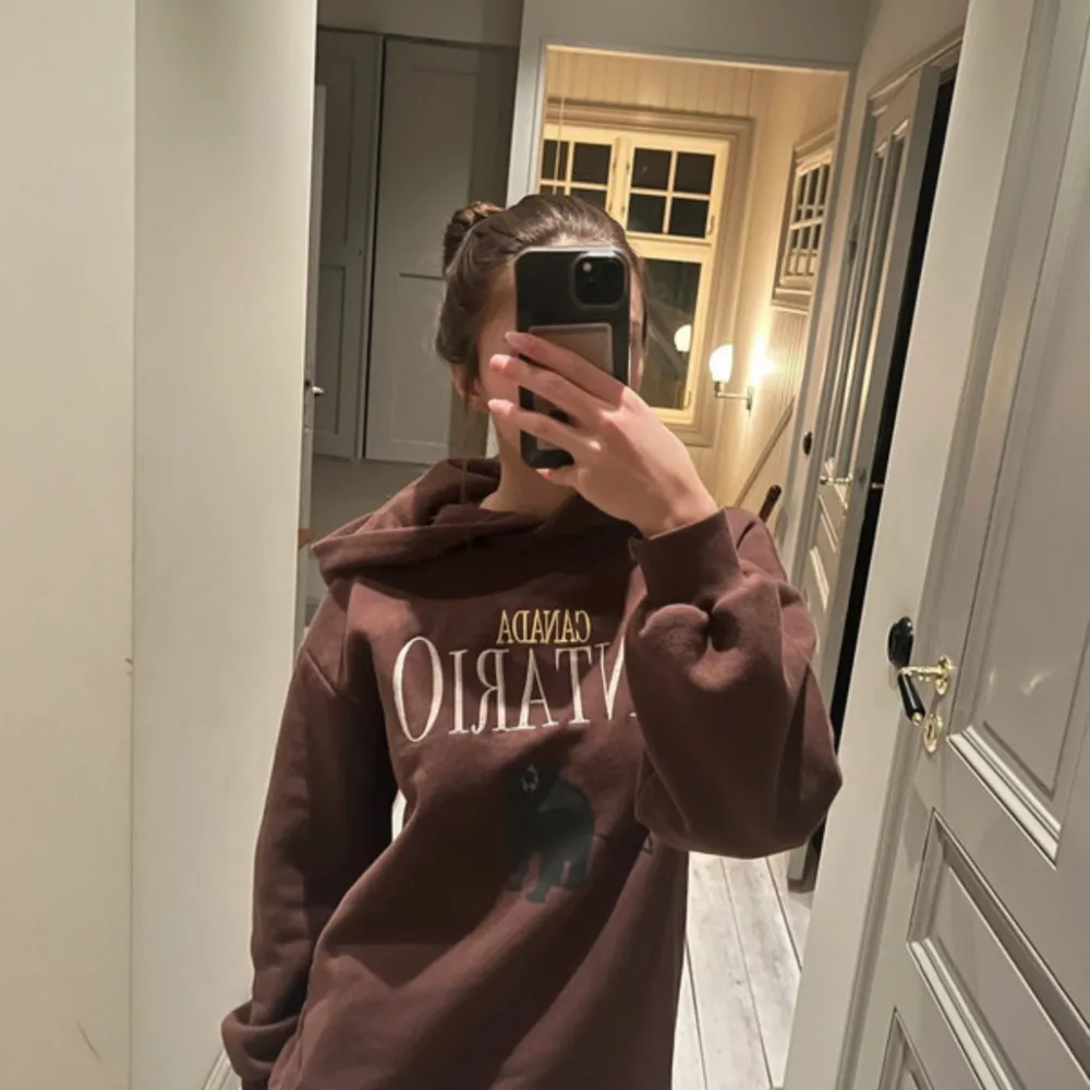 Säljer en brun hoodie med texten 'CANADA ONTARIO' och en björntryck på framsidan. Den är supermjuk som alla Gina hoodies och perfekt för kalla dagar. Klassisk passform med en stor ficka fram och en mysig huva. Perfekt myströja🐻Hoodien är i superbra skick och har inga täcken på användning då jag bara haft den två tre gånger när jag bara vart hemma.. Tröjor & Koftor.