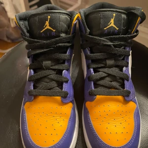 Nike Air Jordans i lila och gul - Säljer ett par Nike Air Jordans i mycket bra skick. Skorna har en cool färgkombination av lila och gul med svarta snören. Perfekta för både vardag och sportiga tillfällen. De har en klassisk design med den ikoniska Air Jordan-loggan på plösen.