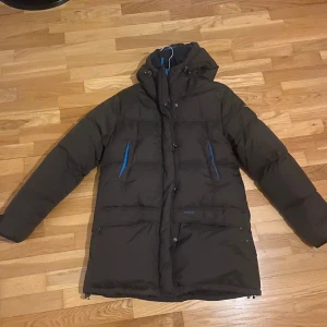 Peak performance jacka  - Brun varm dun jacka i jättefint skick. Liten skada som sytts ihop, syns inte när man har på sig jackan då armen täcker, se bild.  