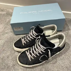 Snygga Philippe Model sneakers i svart och vitt med coola detaljer. Skorna har en klassisk snörning och en bekväm passform. Perfekta för både vardag och fest! De är i bra skick och kommer med originalkartong.  Passar den som har en storlek större om det är så!