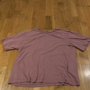 Rosa t-shirt från 157 - Säljer en enkel och bekväm smutts rosa t-shirt från 157 i storlek S. Den är gjord av 100% bomull och har en normal passform med korta ärmar. 