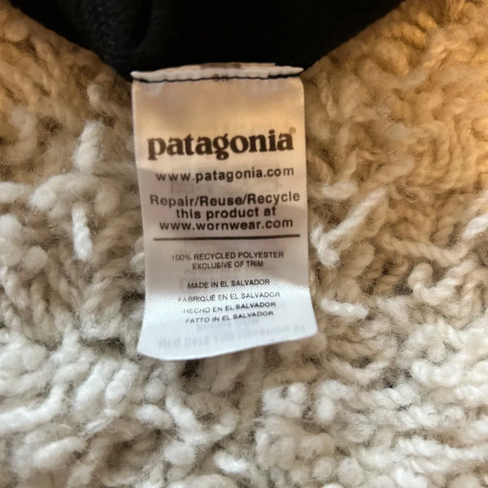 Säljer en svart fleece tröja från Patagonia i storlek L. Den har en dragkedja vid halsen och broderad text 'DeLille Cellars' på bröstet. Perfekt för kyliga dagar och gjord av 100% återvunnen polyester. Supermjuk och bekväm! Women size. Tröjor & Koftor.