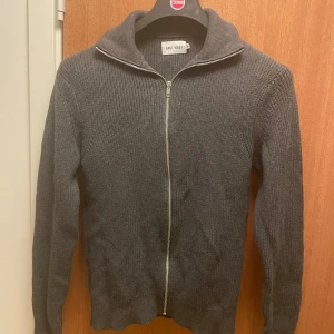 Grå stickad kofta från East West - Säljer en stilren grå stickad kofta från East West. Nypris: 999, Mitt Pris 299. Endast använd en gång. Perfekt för kyliga höst- och vinterdagar. Passar både till vardags och lite mer uppklädda tillfällen. Bara att skicka iväg ett meddelande vid intresse!