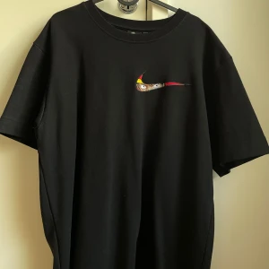 Svart t-shirt med broderad logga - Säljer en svart t-shirt från Nike med en cool broderad logga på bröstet. Den är kortärmad och perfekt för både vardag och träning. Materialet känns mjukt och skönt mot huden. T-shirt är översized ock knappt använt. Kontakta för mer information 