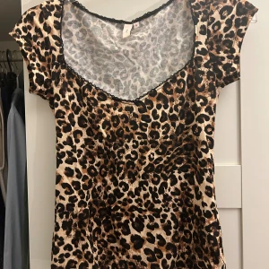 Leopardmönstrad topp med spetsdetaljer - Säljer en snygg leopardmönstrad topp i storlek S. Den har en v-ringad hals med svarta spetsdetaljer och korta ärmar. Perfekt för en utekväll eller fest! Helt ny endast testad❤️