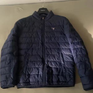 Mörkblå Gant jacka i storlek 145/152  - Detta är en mörkblå gant jacka utan luva. Det är en dunjacka utan luva. Storleken på jackan är 146/152 och mellan ålderns 12-13 för killar. 