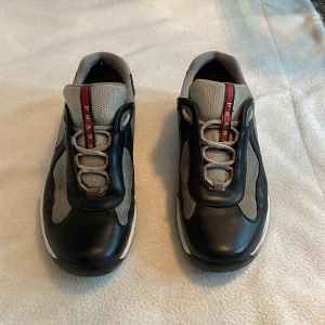 Prada America cup original skor - Hej! Säljer ett par Prada America cup original skor. Skick 8/10 något smutsiga och en liten repa på tån men syns ej. Sälje togs oanvänding har bara stått. Storlek 43 och true size. (Bildreferens med). Skriv om ni har några frågor🤗