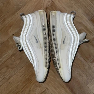 Nike Air Max 97 - Ett par vita Nike Air Max 97’s jag varit mycket försiktiga med och använt väldigt få gånger. Säljer pga de används så sällan! De ser i princip nya ut i verkligheten.  Nypris: 2 399 kr