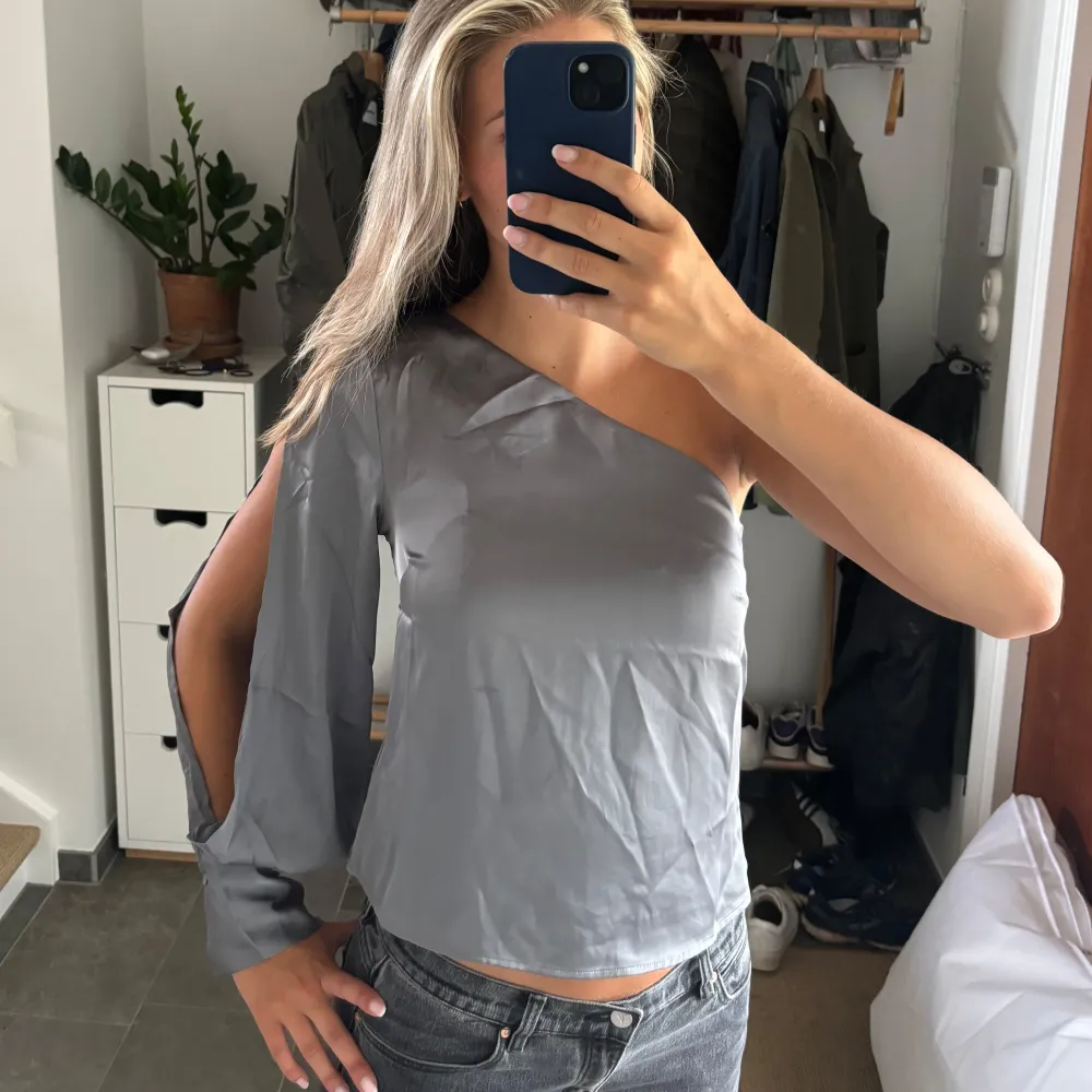 Superfin grå oneshoulder blus från H&m i satin. Aldrig använd med prislappen kvar och är i storlek S🩷. Blusar.