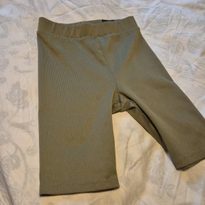 Olivgröna ribbade shorts - Säljer ett par olivgröna ribbade shorts från Divided. De är superbekväma och perfekta för en avslappnad dag. Shortsen har en elastisk midja och är gjorda av en mjuk polyesterblandning. Perfekta för vår och sommar!