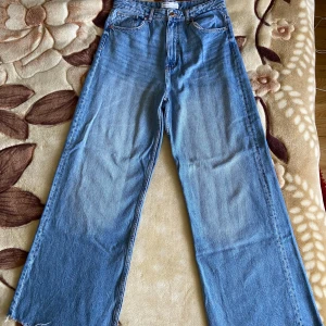Blå vida jeans från Bershka - I använt men mycket fint skick! Fungerande dragkedja och hela byxfickor. Högmidjade och bekväma. Ingen stretch.   MÅTT Midja: 38,5cm Innerbenslängd: 75,5cm Höfter: 57cm Totallängd: 108cm  Stl. 38 100% bomull Nypris: 599 kr 