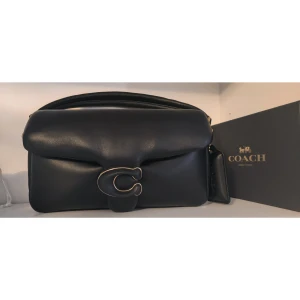 Coach Pillow Tabby crossover 26 - Coach Pillow Tabby 26 i Svart. Inköpt 2021, använts ute på middag 1 gång och har sen dess förvarats i sin dustbag i mitt vitrinskåp, ser gärna att denna fina väska kommer till användning!