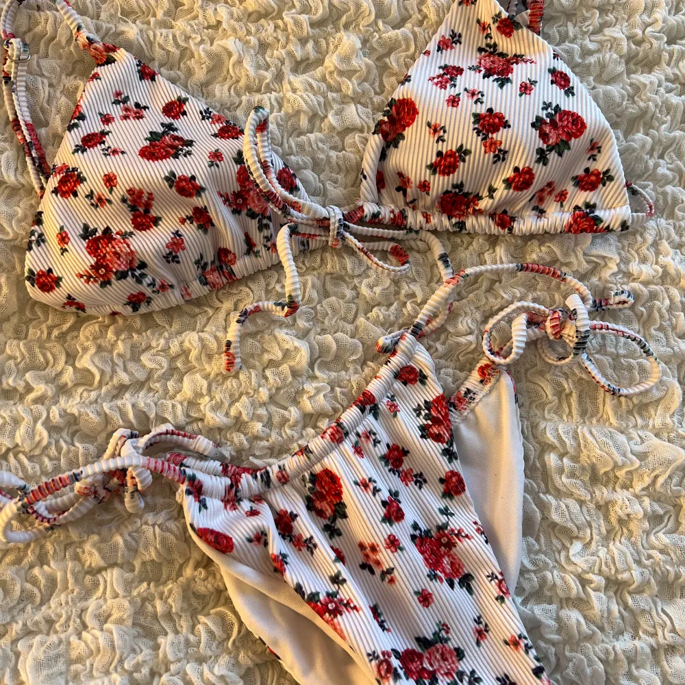 Säljer en superfin bikini med blommigt mönster. Bikinin har knytband både på toppen och nederdelen, vilket ger en justerbar passform. Materialet är ribbat. Bikinin är aldrig använd och i nyskick.. Övrigt.