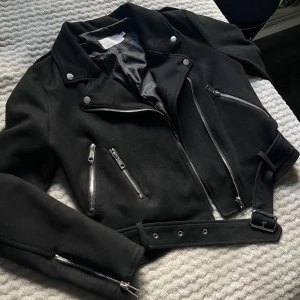 Svart biker jacka mocka från Nelly - Biker jacka i mocka, jättefint skick. Använd få gånger! Perfekt till hösten 😍 kan stängas med dragkedja och har även bälte 🎀