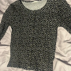 Blommig H&M topp med knappar  - Den är i barn strl 158-164 för mig som brukar ha xs-M så passar den. Skulle dock säga mer xs i strl ☺️
